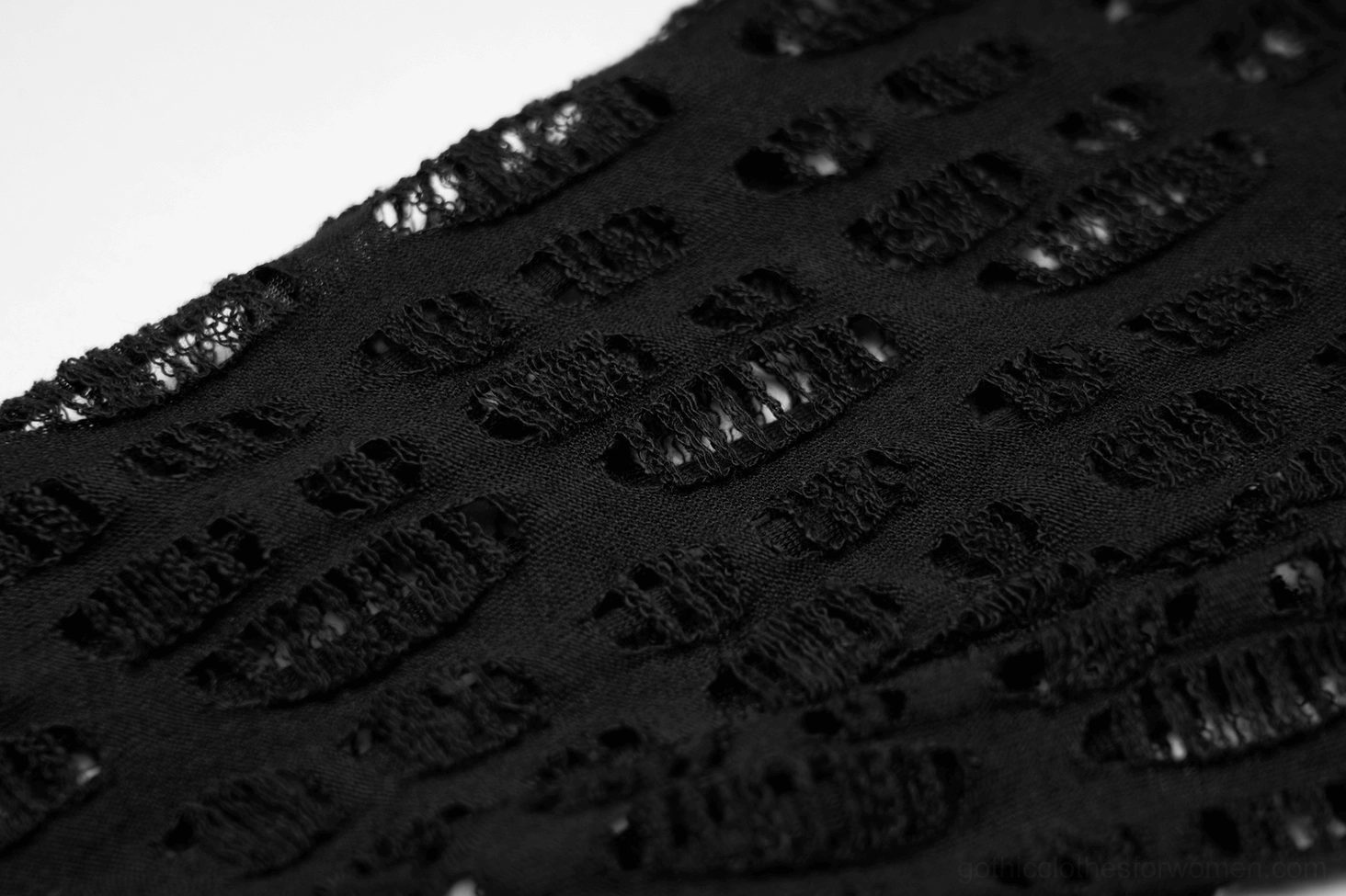 Macro detail view of repeating frayed cut-out mesh pattern on black fingerless gloves