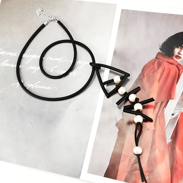 Fish bone pendant necklace flat lay on fashion magazine pages, featuring silver lobster clasp and pearl drop accents in gothic style