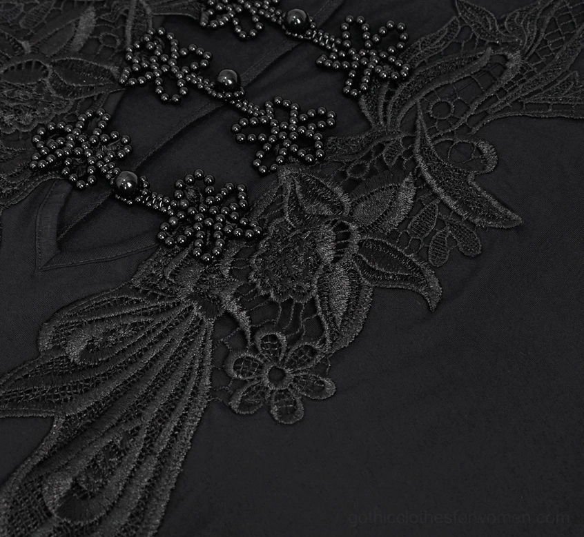 Close-up macro view of intricate floral lace and beaded cross decorations on dress bodice, showing delicate stitching and embellishment work
