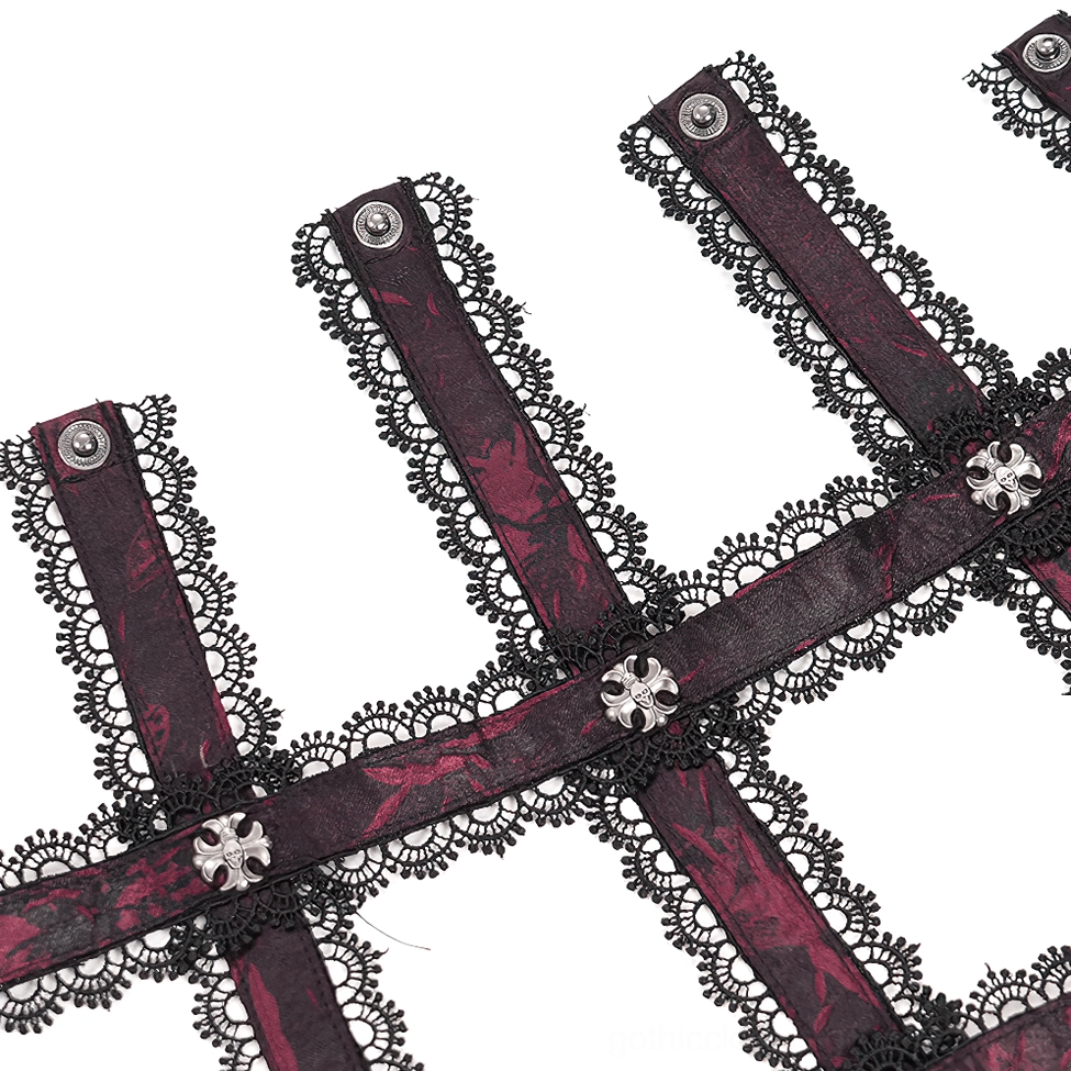 Garter strap accessory detail with lace trim, cross charms, and red-black jacquard brocade fabric close-up