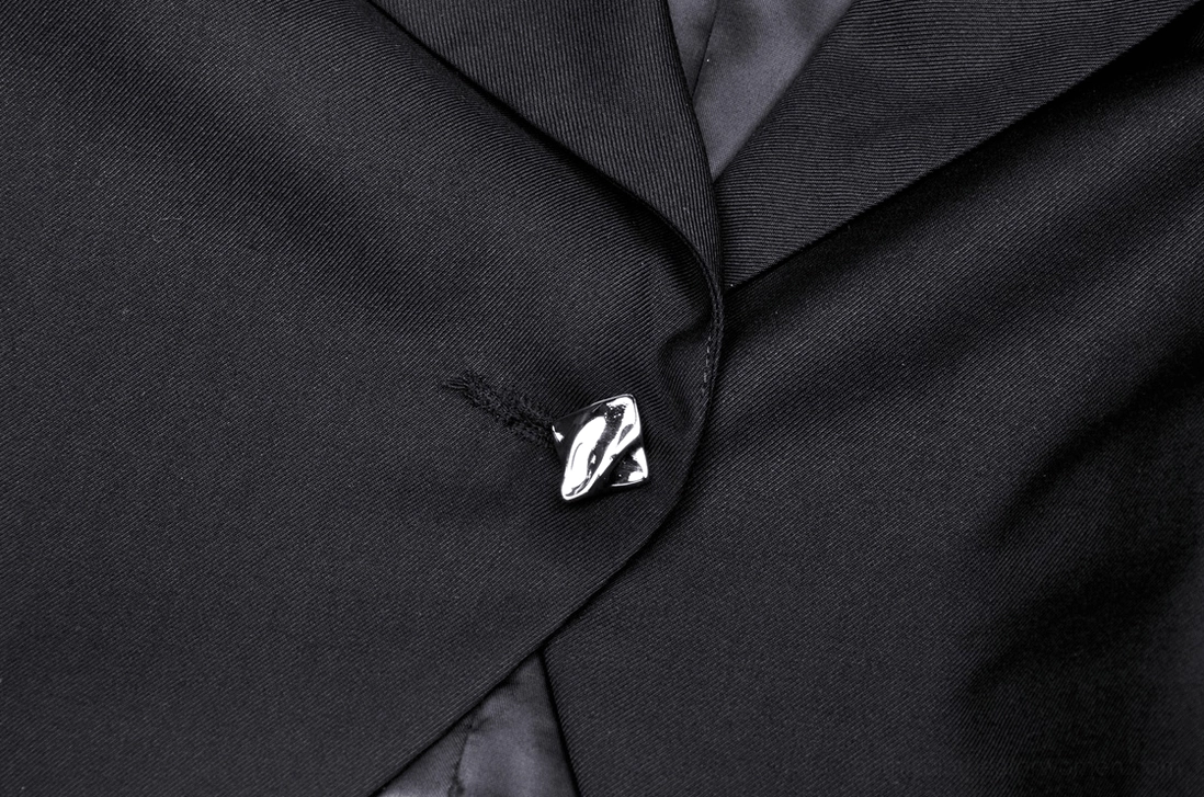 Close-up detail of skull-shaped metal button closure on black cropped goth jacket