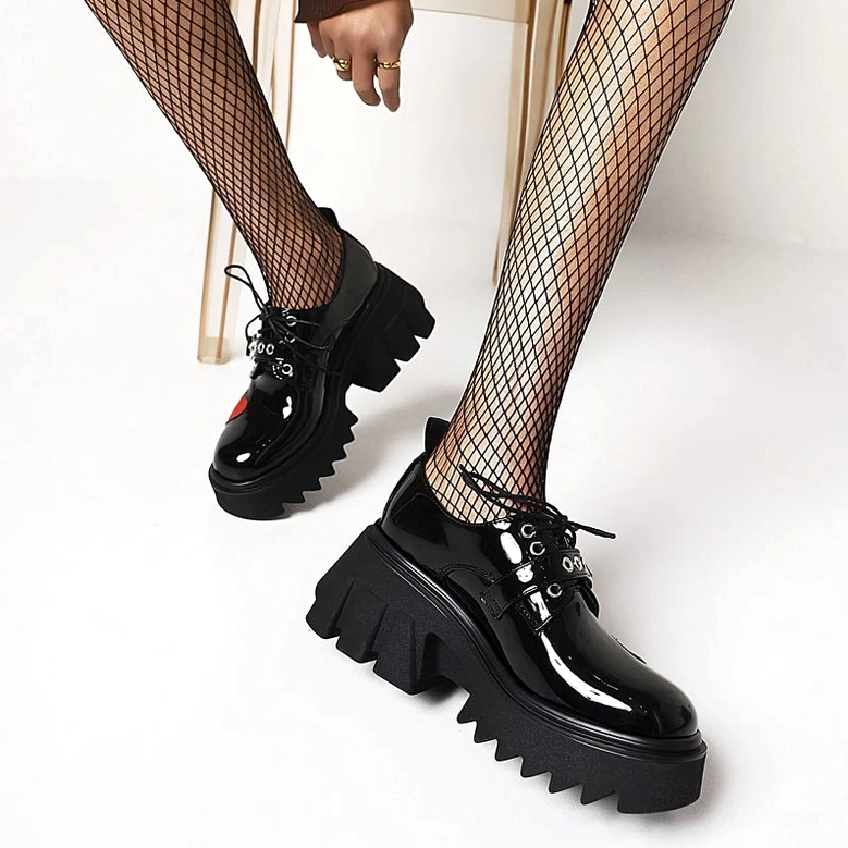 Black leather platform lace-up shoes on model with fishnet stockings, showcasing the side profile and aggressive lug tread design