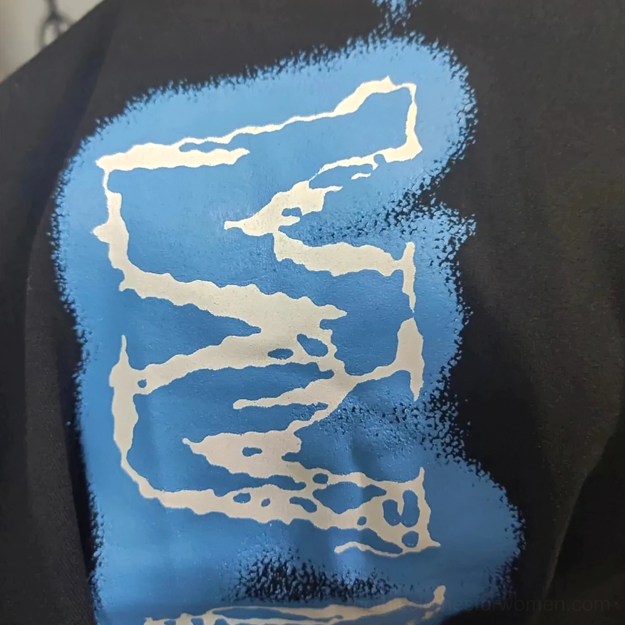 Detailed close-up of blue graffiti lettering and distressed print on black gothic anime jogger pants