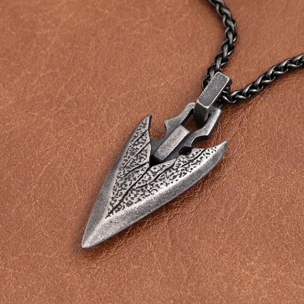 Dark silver gothic arrowhead pendant on black wheat chain - leather background with wood