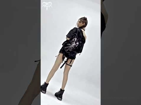 Alternative fashion model in punk style wearing gothic demon backpack with casual dark outfit, full side view
