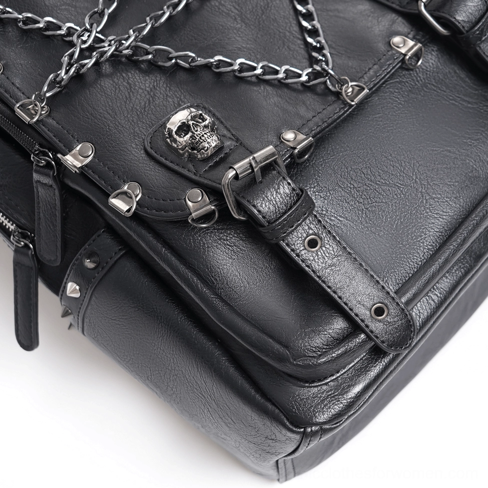 Side close-up detail of black gothic backpack corner showing metal skull hardware, buckle fasteners and leather texture