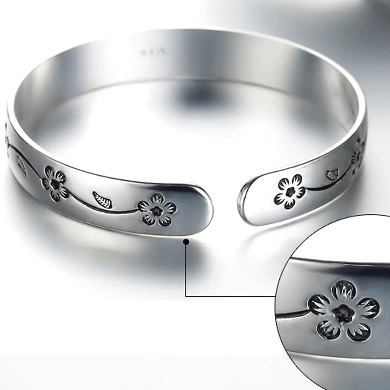 Close-up top-down view of silver bangle bracelet showing inner marking and detailed gothic flower engraving texture