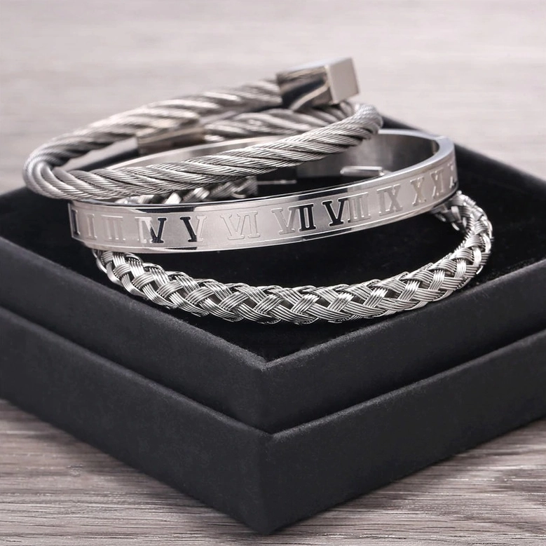 Top-down view of 3-piece silver gothic bangle set with Roman numeral engravings in gift box, luxury dark aesthetic metal bangles