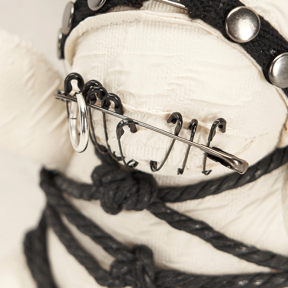 Close-up macro photography of gothic bear safety pin mouth and black rope knots