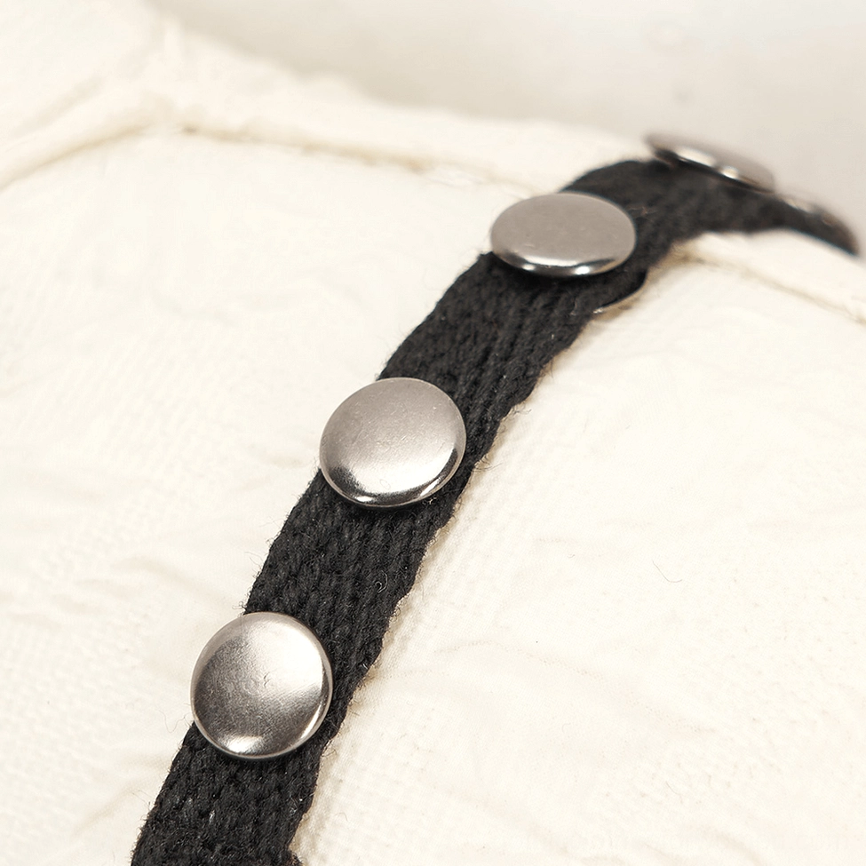 Detailed macro shot of gothic bear harness with silver metal rivets and black fabric