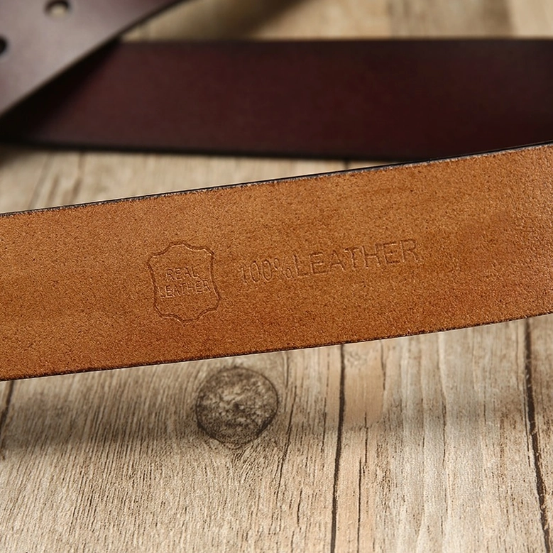 Gothic leather belt inner lining, showing tan leather backing and embossed authenticity mark on wooden surface