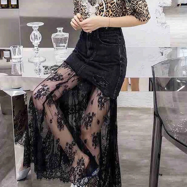 Black gothic denim mesh midi skirt with lace detail - seated side view showing distressed denim and sheer hem in modern bar setting