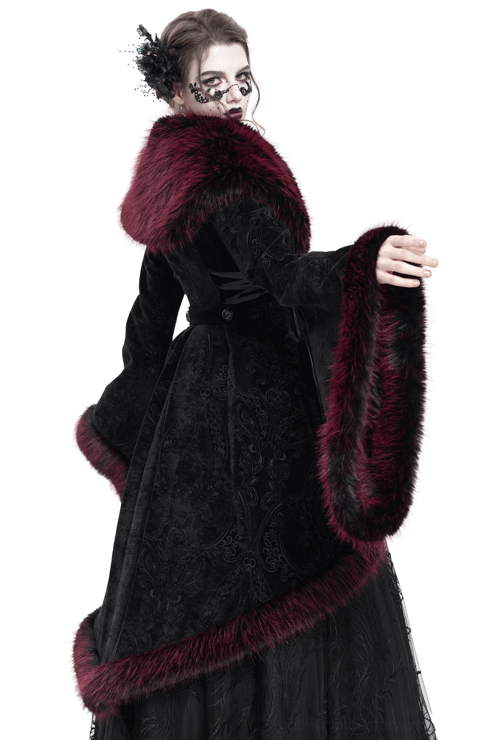 Rear three-quarter view of black velvet gothic coat displaying high-low hemline, fur-trimmed back details, and lace side panels