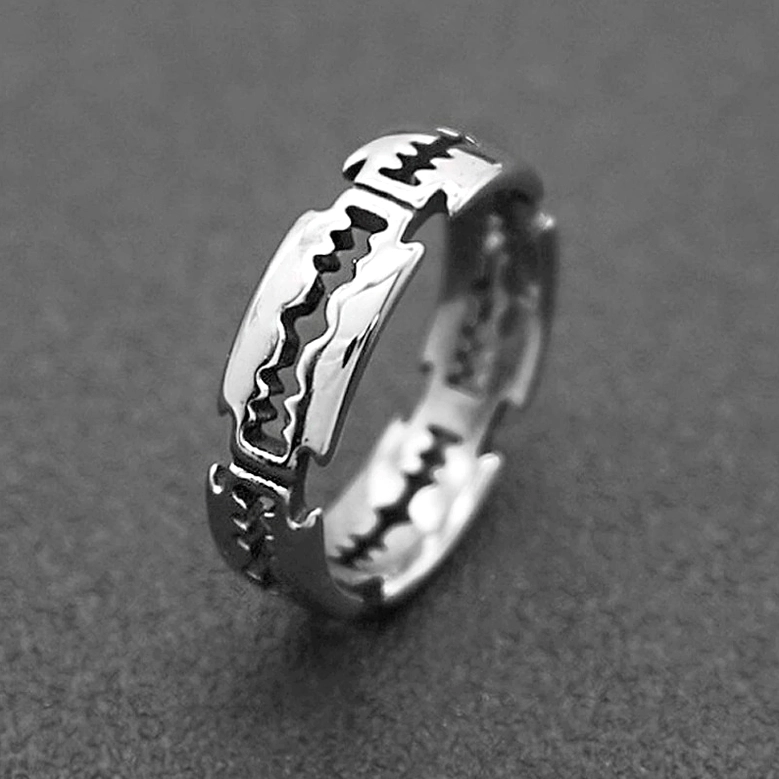 Clear sawtooth blade pattern ring in sleek silver tone, oblique side close-up on dark matte background