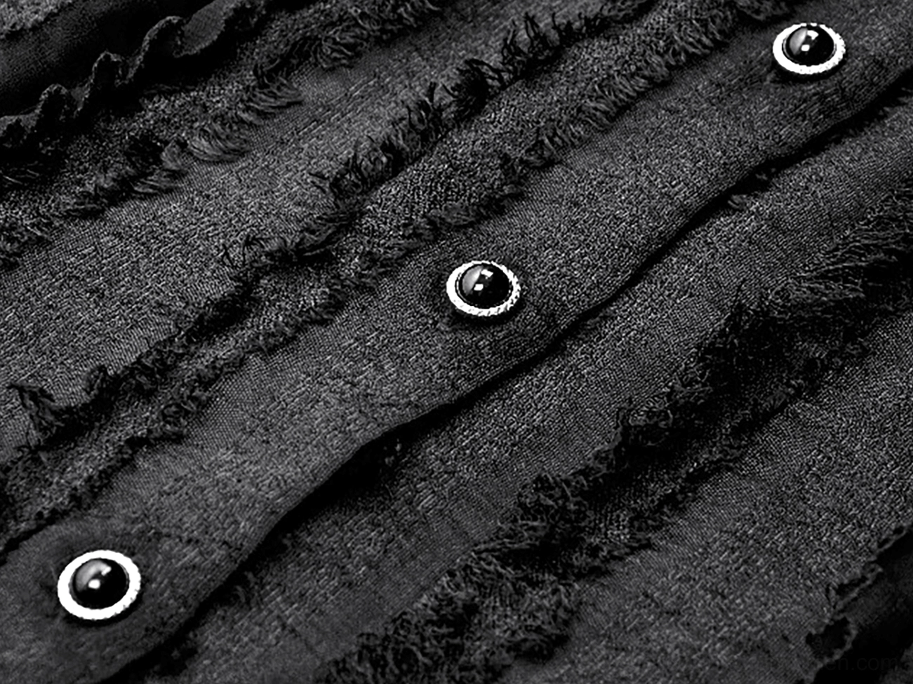 Close-up detail of black gothic lace blouse front button placket, showing black frayed fabric and polished metal decorative button accents