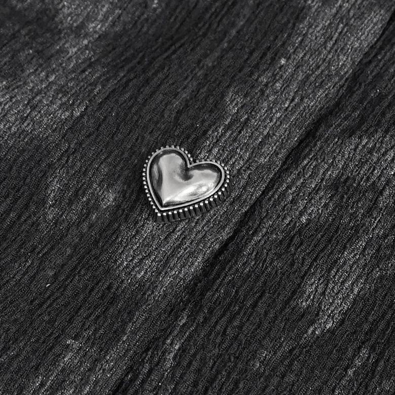 Texture close-up of black gothic blouse fabric showing wrinkled polyester blend and heart button