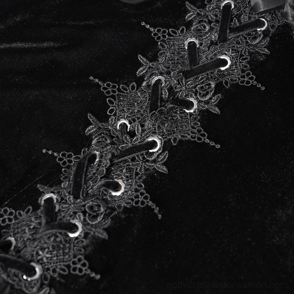 Macro close-up photograph of gothic blouse front lace-up closure showing velvet fabric texture, lace embroidery, and metal eyelet fasteners
