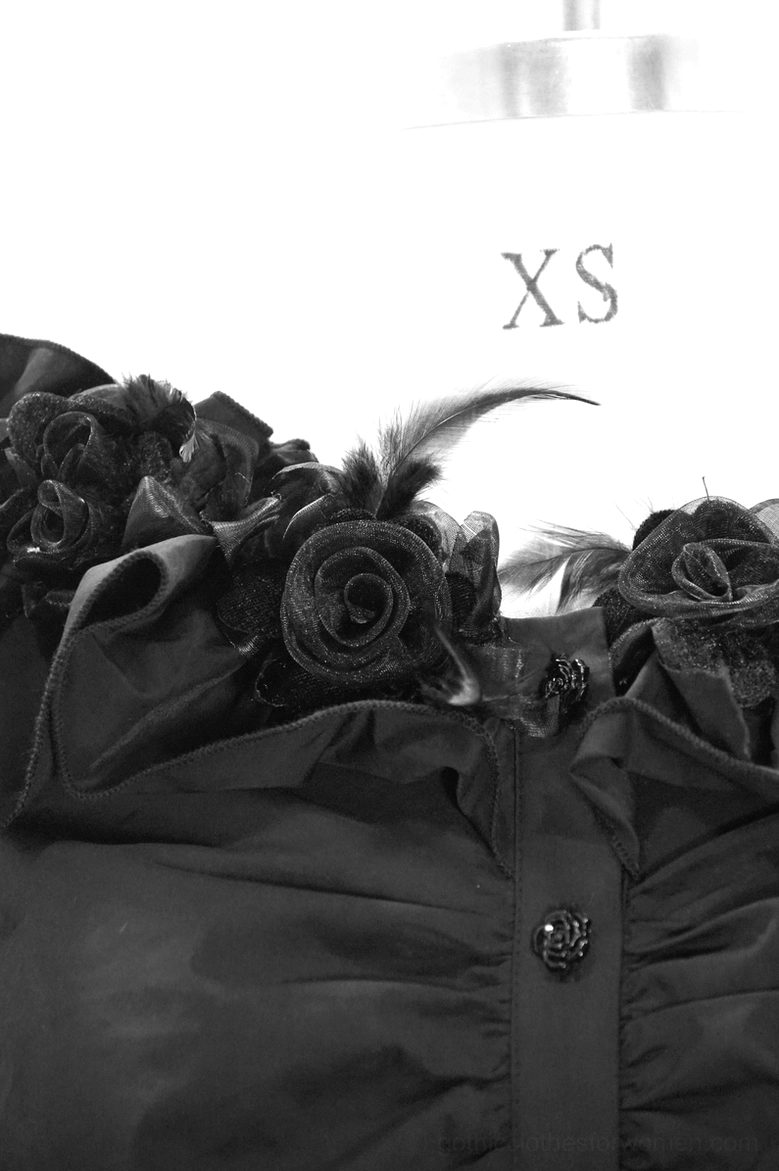 Close-up detail of gothic blouse neckline featuring 3D dimensional rose appliqué with feather accents, decorative rose-shaped buttons, and ruffled off-shoulder trim