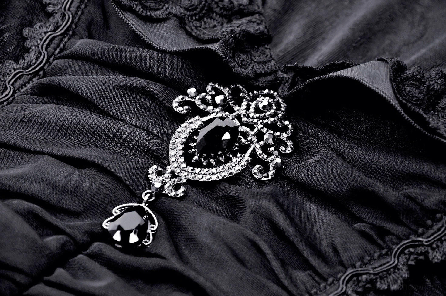 Close-up of black Victorian gothic blouse bodice showing vertical ruched stitching pattern, embroidered fabric texture, and architectural construction detail