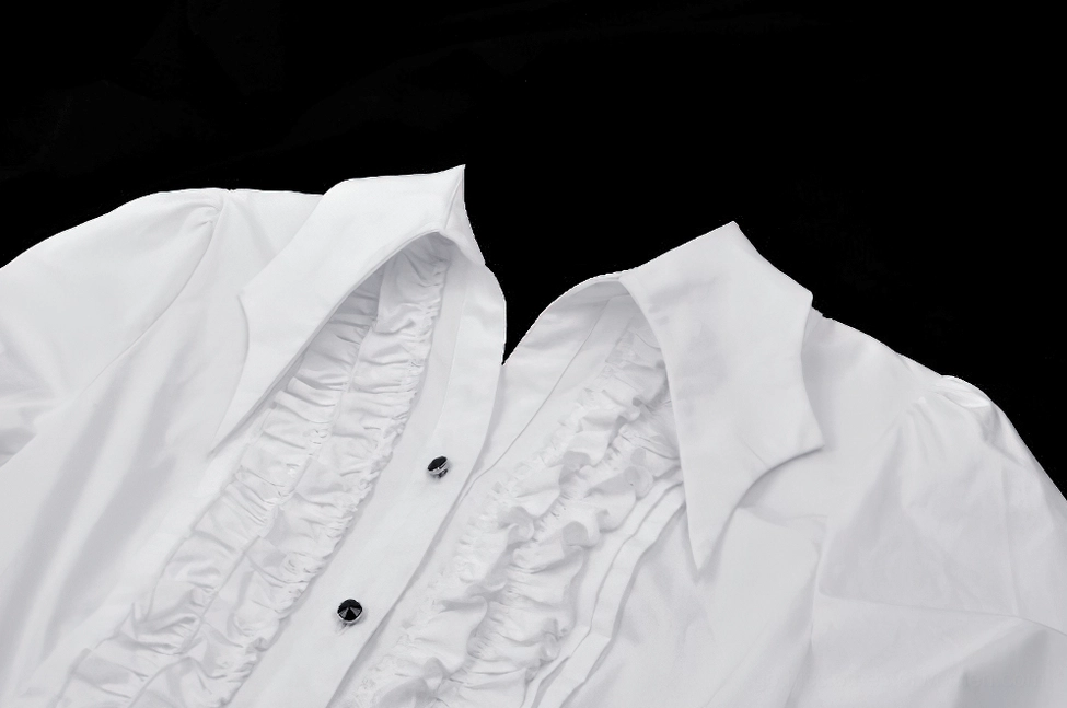 Close-up macro view of white gothic blouse collar and layered ruffled placket with black round buttons against black background
