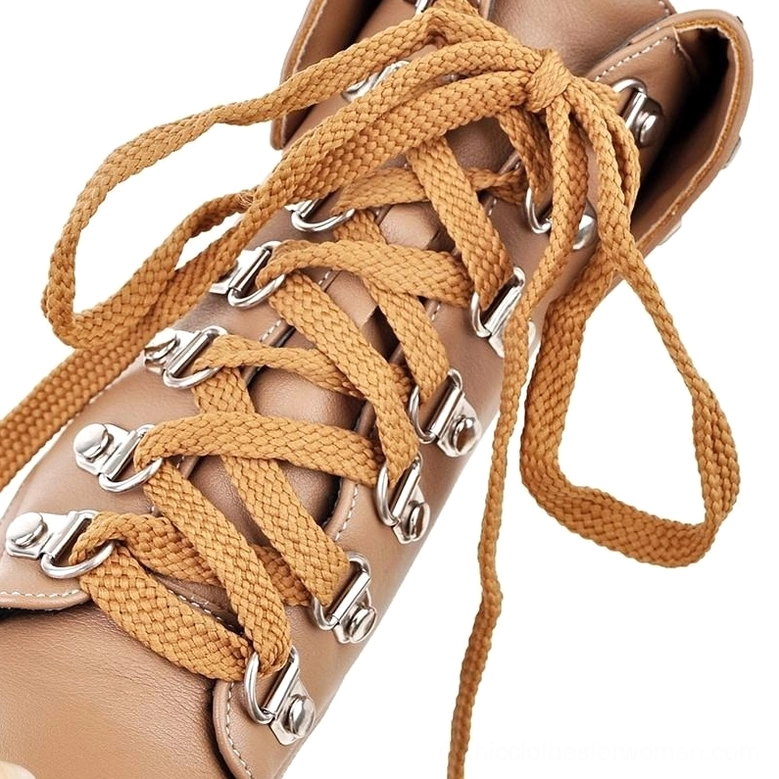Lace-up boot eyelets close-up detail, showing woven tan laces threaded through reinforced silver metal eyelets, industrial gothic construction