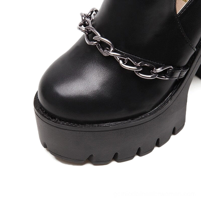 Close-up detail of black gothic boot toe and vamp with polished PU leather and metal chain trim