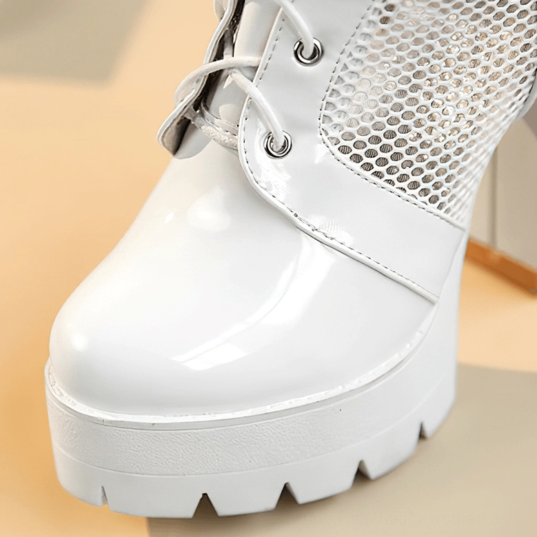 Close-up of white gothic platform boots toe cap showing shiny patent leather and mesh upper panel details