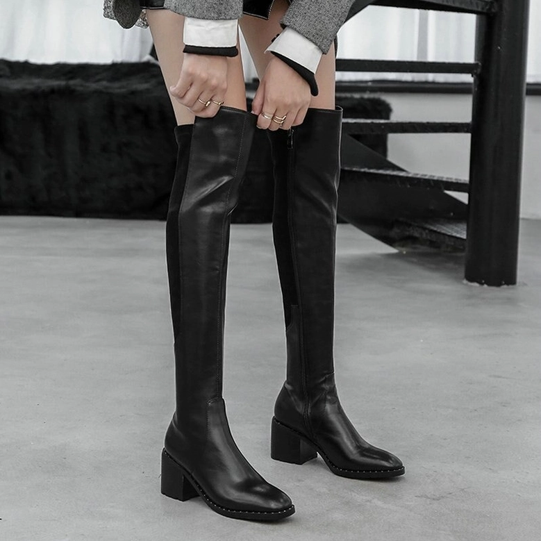 Female model in black leather over-the-knee gothic boots with round toe and commanding block heel, front standing view