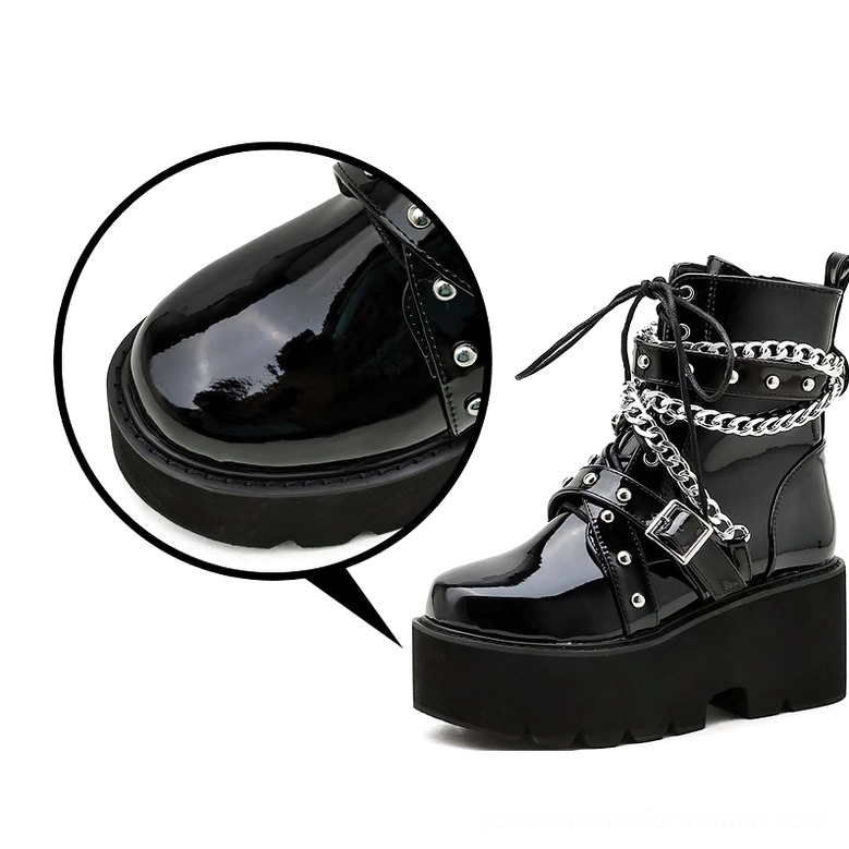 Close-up detail of black gothic boot toe cap featuring polished patent leather and decorative metal rivets