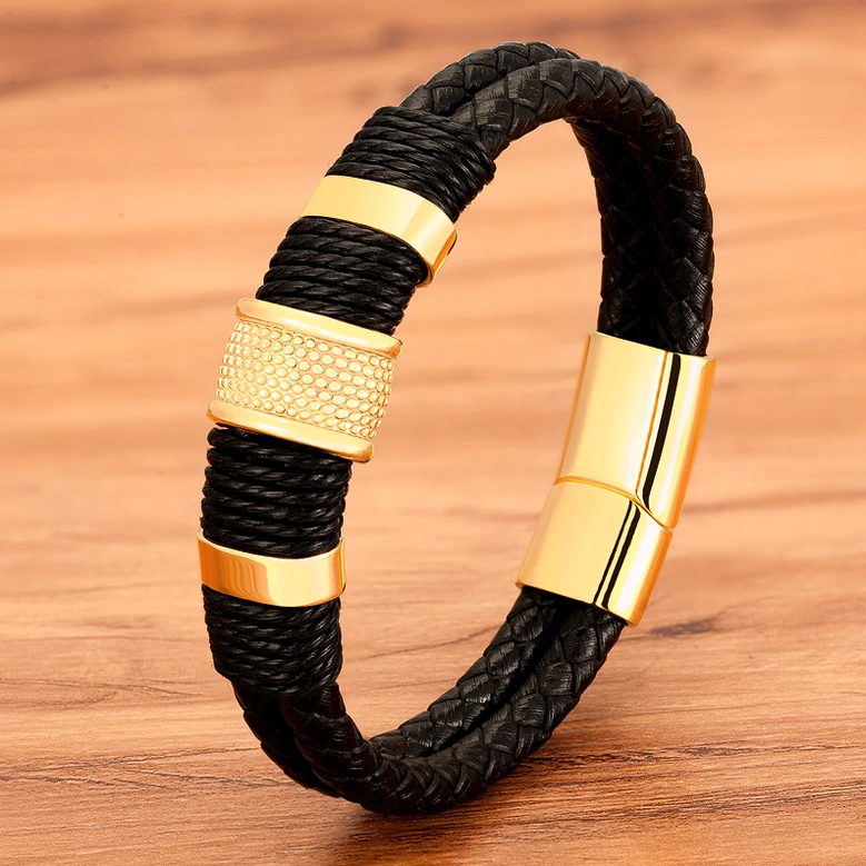 Black leather gothic bracelet with gold-plated magnetic clasp hardware on wooden background, oblique front view