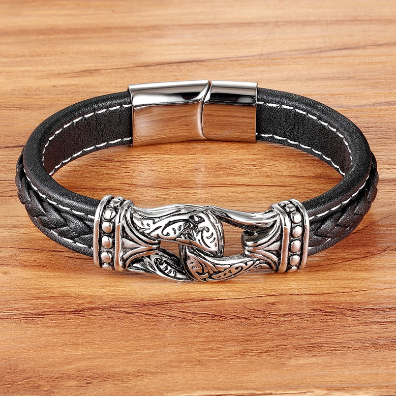 Black leather gothic bracelet displayed on wooden surface, showing stainless steel accents and texture