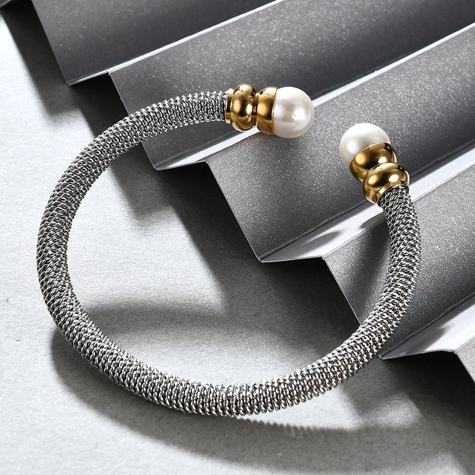 Oblique side view of stainless steel pearl cuff showing dark silver plating and gold hardware details