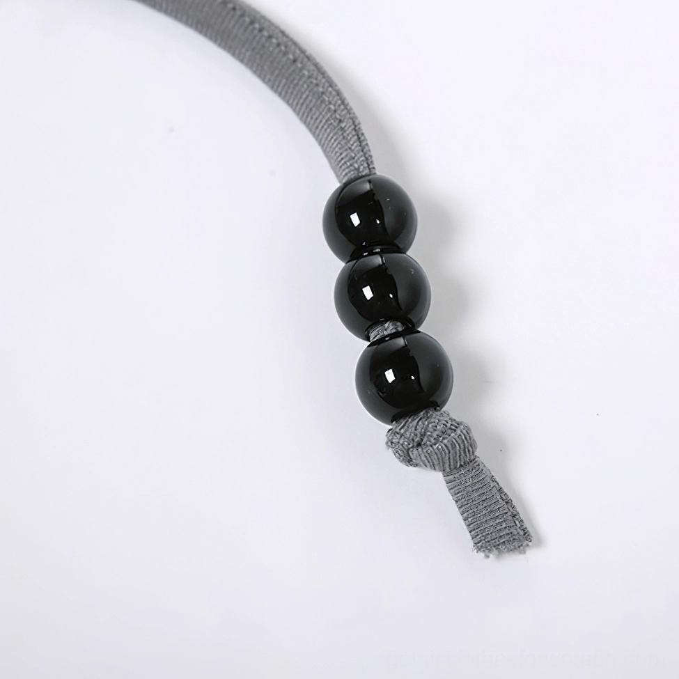 Extreme macro photography of black round bead accents and frayed fabric edges on gothic cami halter strap