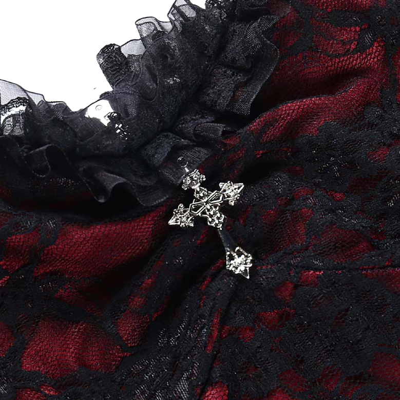 Silver cross charm ornamental detail on gothic lace camisole, close-up of pendant decoration