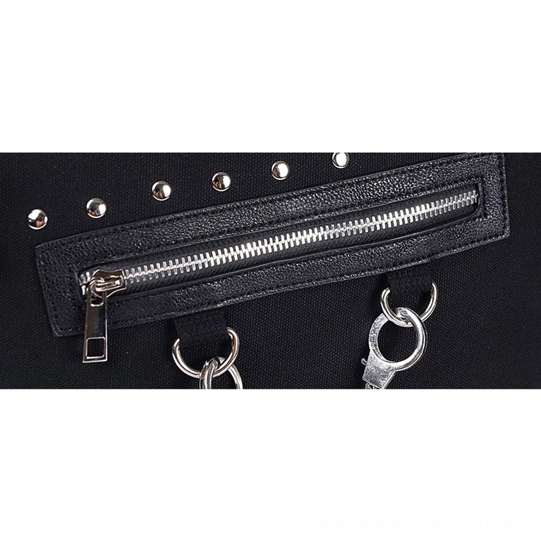 Close-up macro view of metal zipper, studded trim, and handcuff-style ring hardware on gothic canvas tote