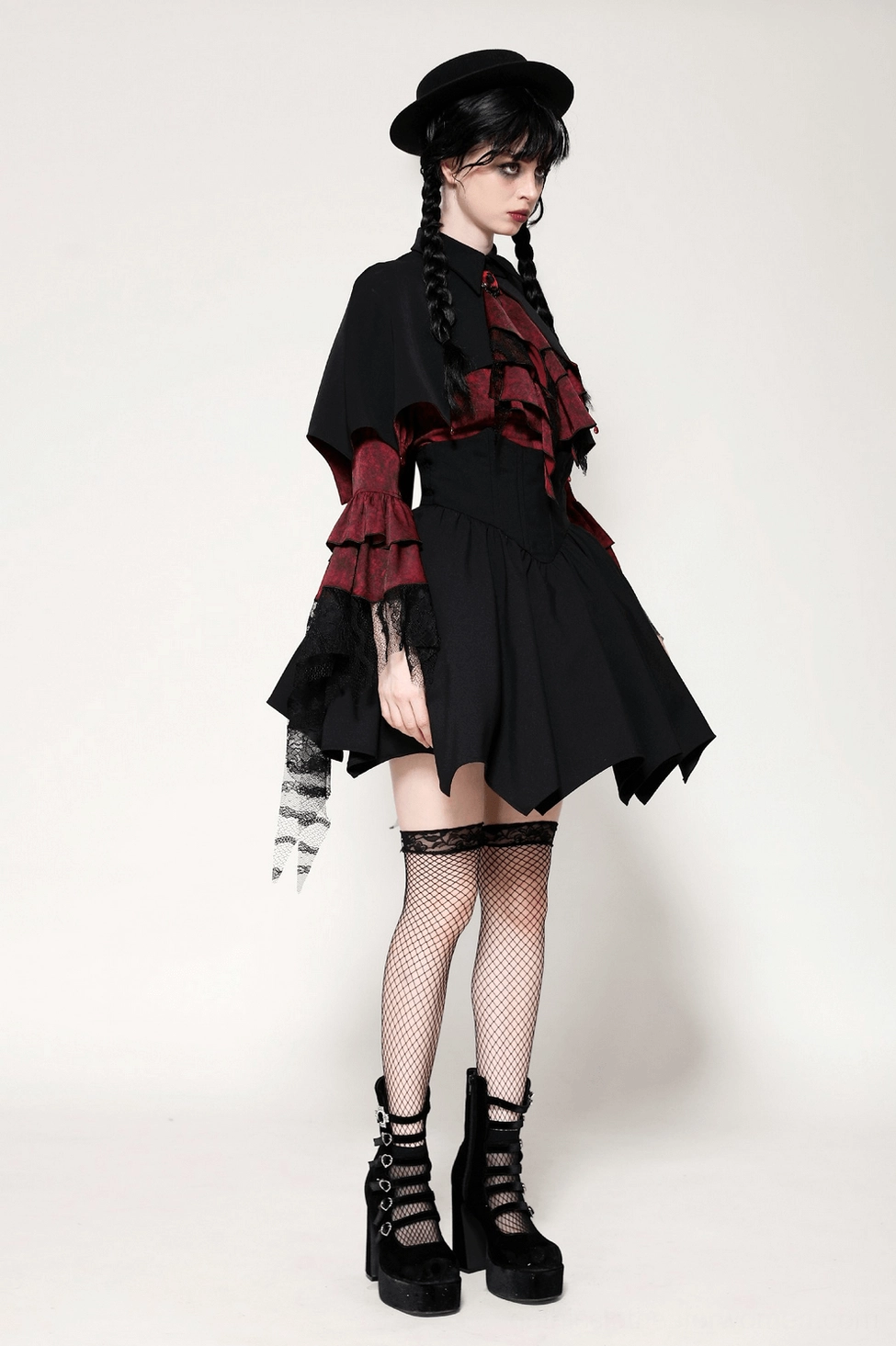 Detailed view of black gothic cape showing matte fabric quality, precision stitching, and jeweled brooch clasp embellishment