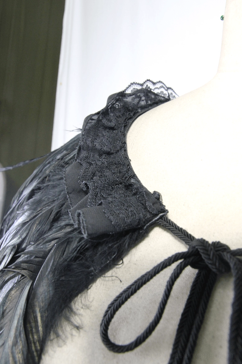 Gothic cape side strap detail showing black braided tie and ruffled lace edge on dress form