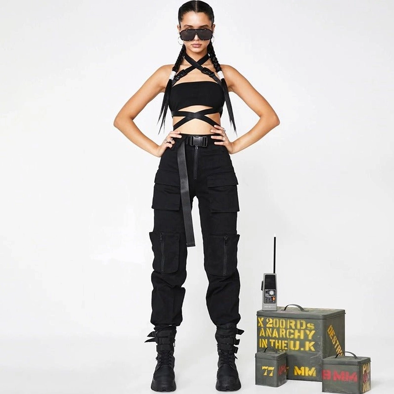 Gothic pants outfit styling - female model wearing black pleated cargo pants with crop top, utility belt and combat boots