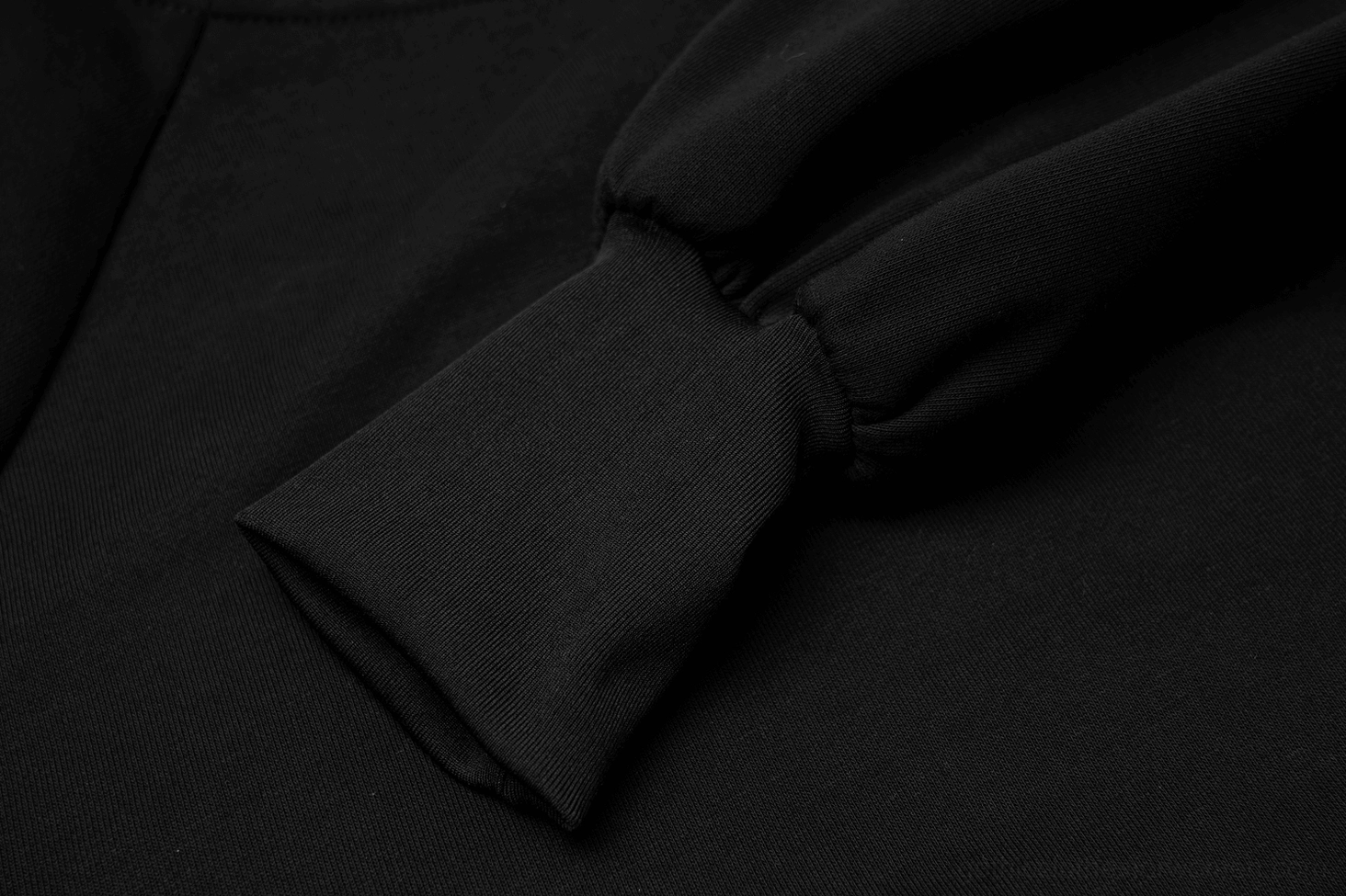 Close-up of elasticated black lantern cuff design showing smooth woven fabric texture and tapered sleeve ending