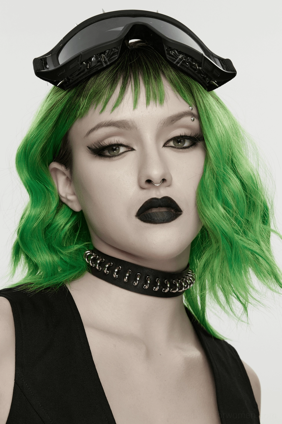 Gothic model with green hair and dark makeup wearing black metal ring choker studio shot