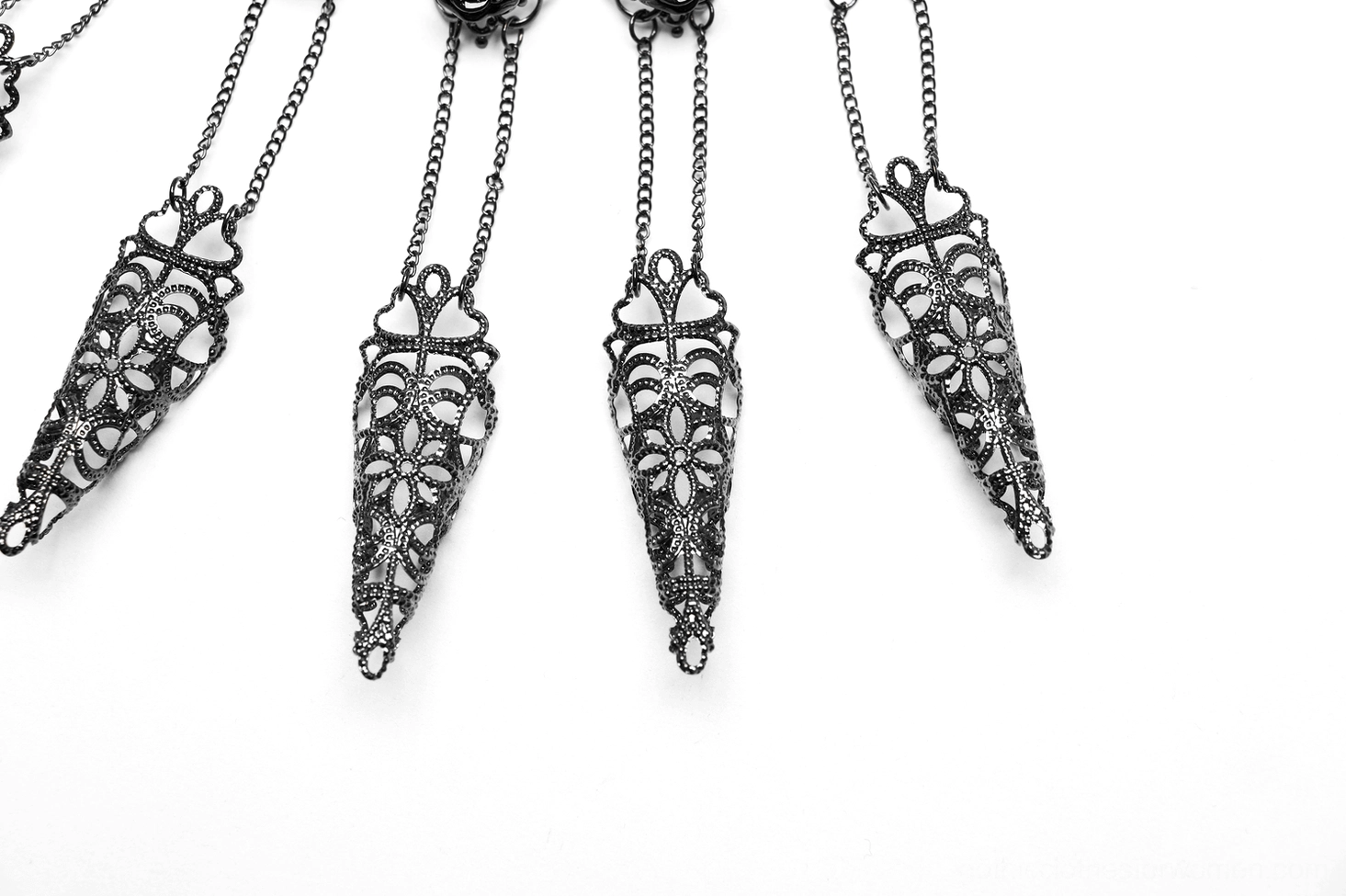 Close-up flat lay of carved black filigree metal claw nail pendants for gothic jewelry, showing four matching sharp-tapered decorative elements
