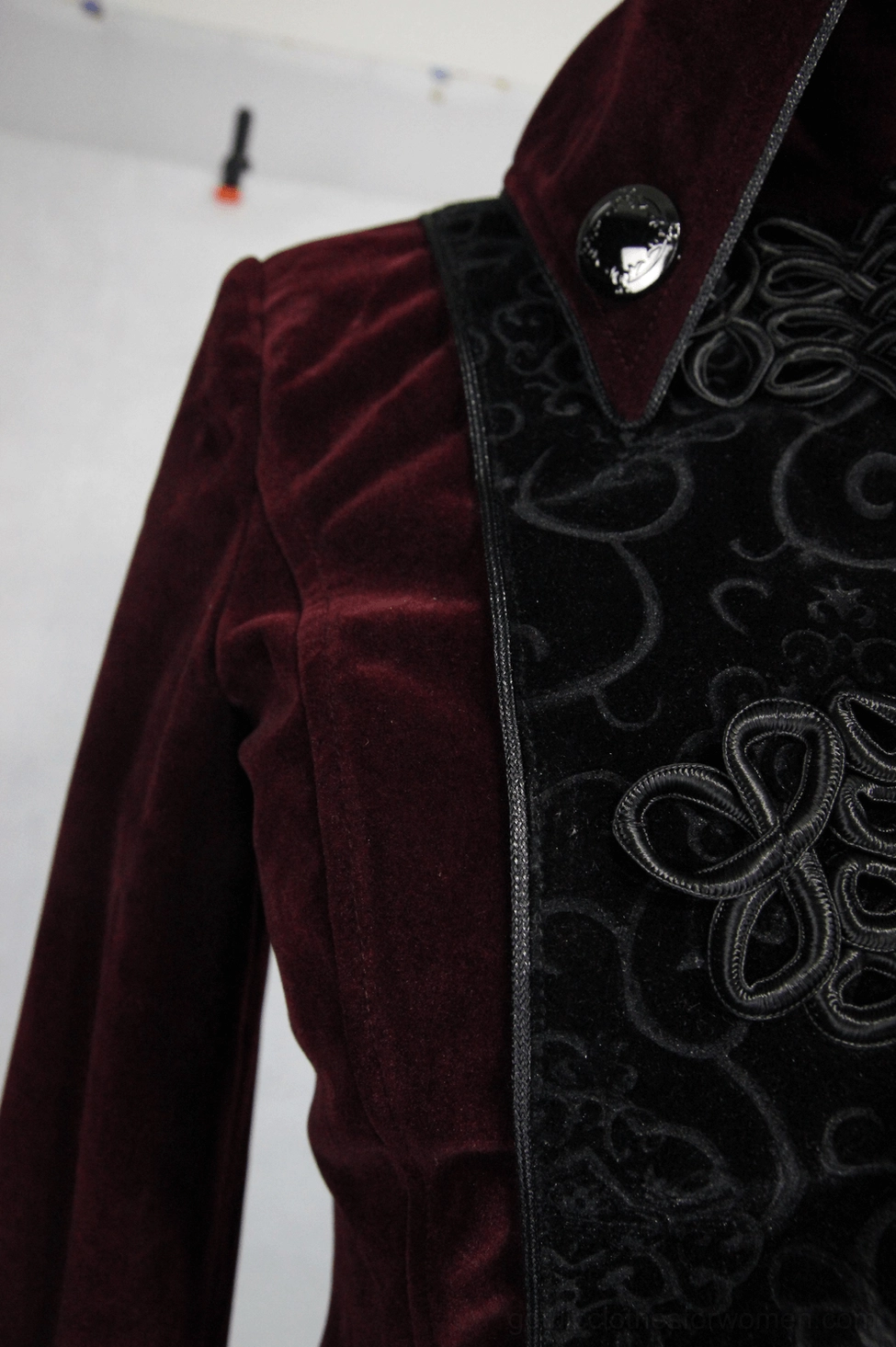 Gothic coat collar and front embroidered panel close-up - decorative gem button, black embossed velvet detailing, intricate gothic embroidery