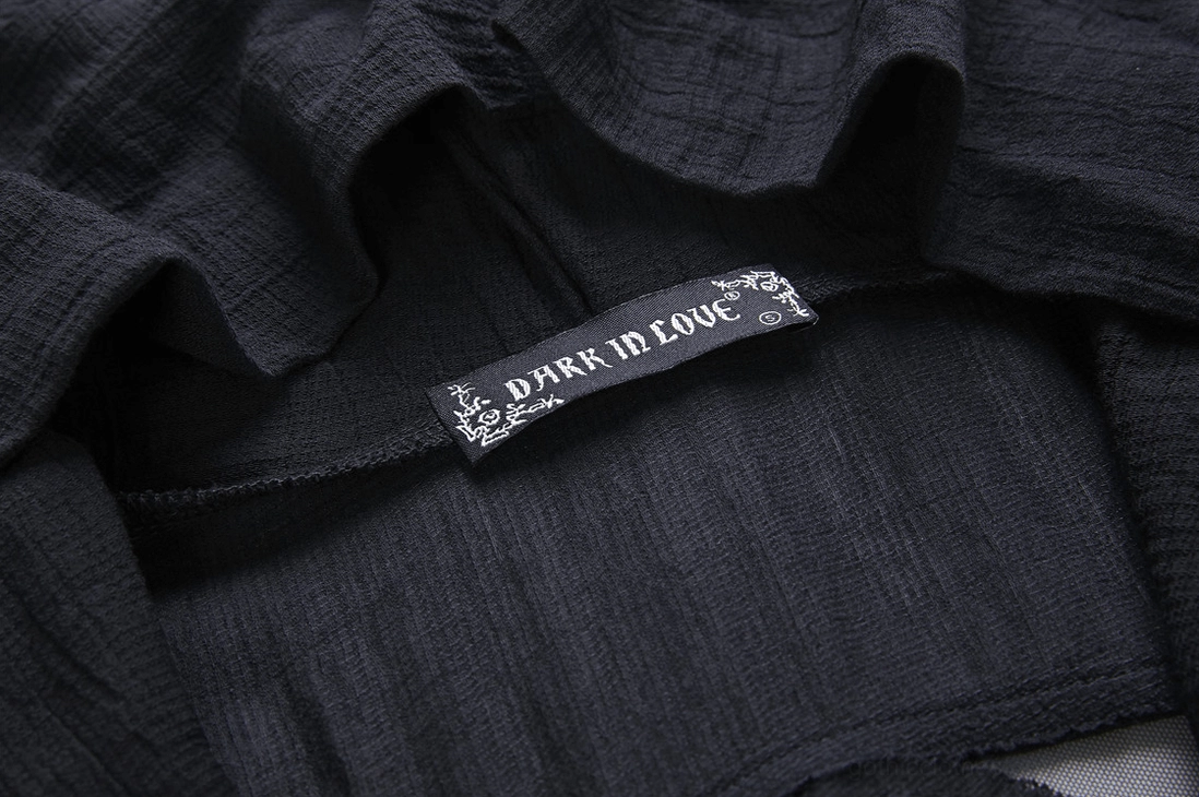 Close-up detail of wrinkled black woven fabric and branded label on gothic trench coat