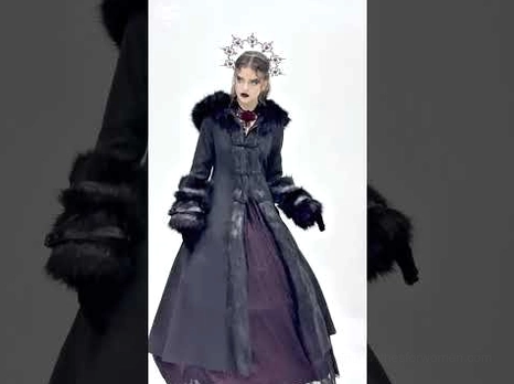 Dark atmospheric gothic winter coat styled on fantasy model with crown headpiece, showcasing formal tailored fit and faux fur luxury accents
