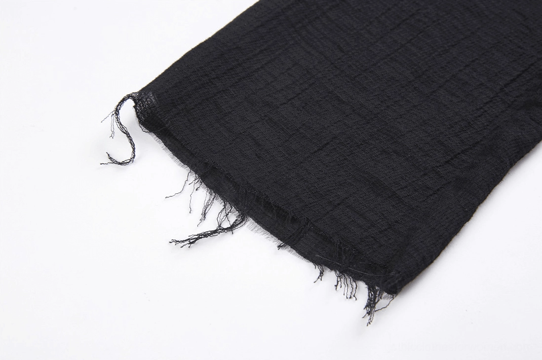 Macro detail of frayed raw-edge hem finish on gothic punk coat showing intentional tattered texture