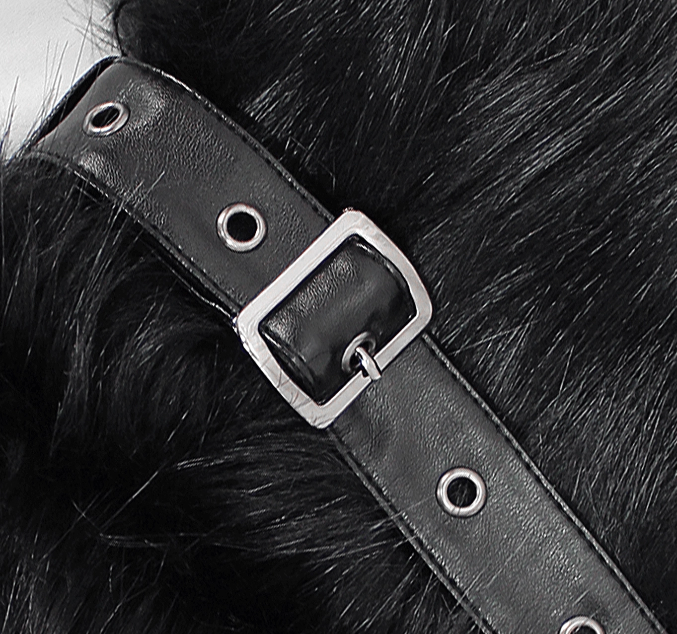 Close-up detail shot of black leather strap with metal buckle and eyelets on gothic coat cuff, showcasing craftsmanship and hardware design