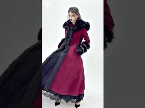 Side profile of burgundy gothic coat on model with upswept hairstyle showing dramatic silhouette and layered hem