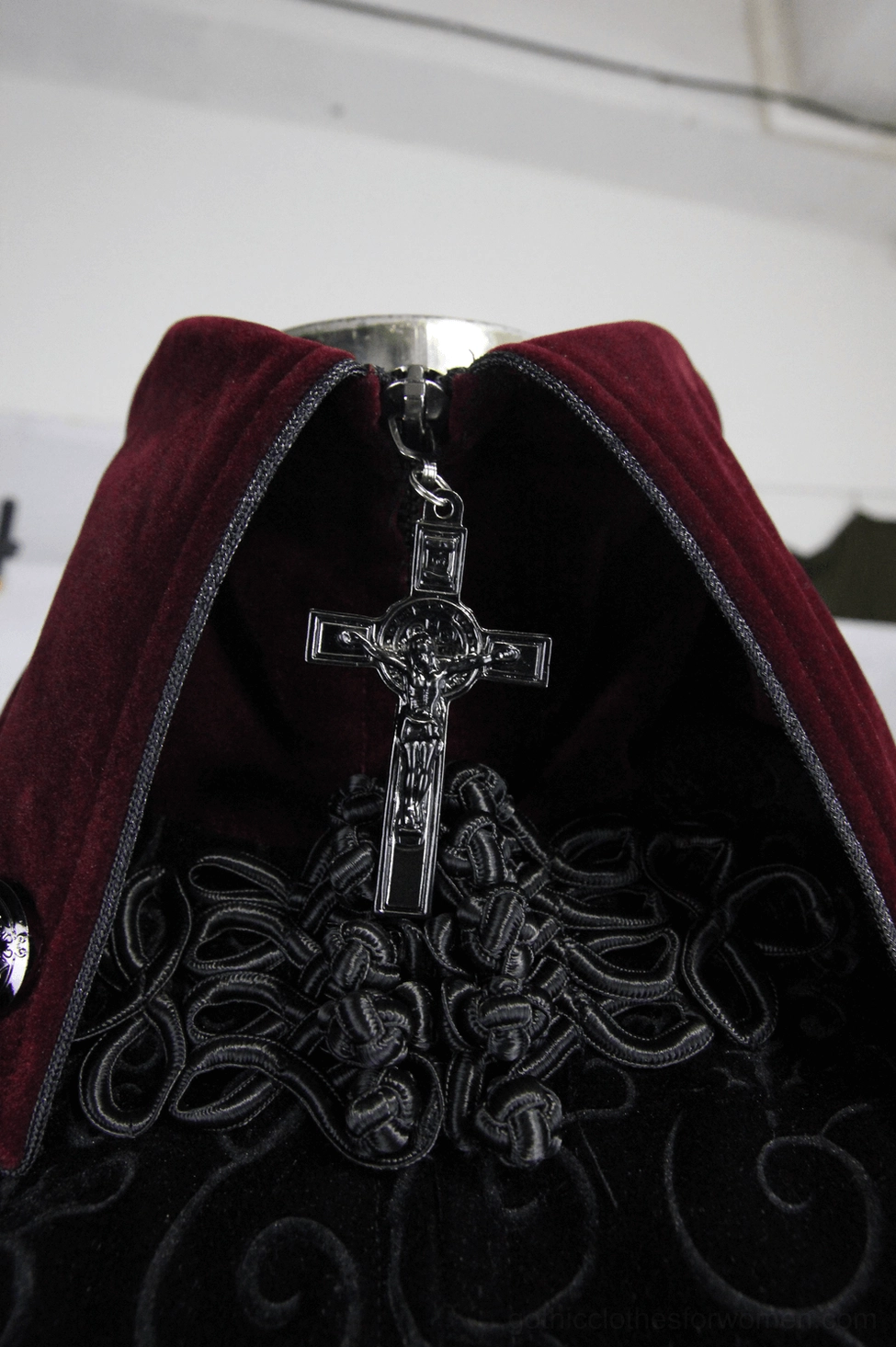 Close-up detail of gothic coat cross zipper and high collar - ornate black embroidery, burgundy velvet fabric, decorative zipper pull
