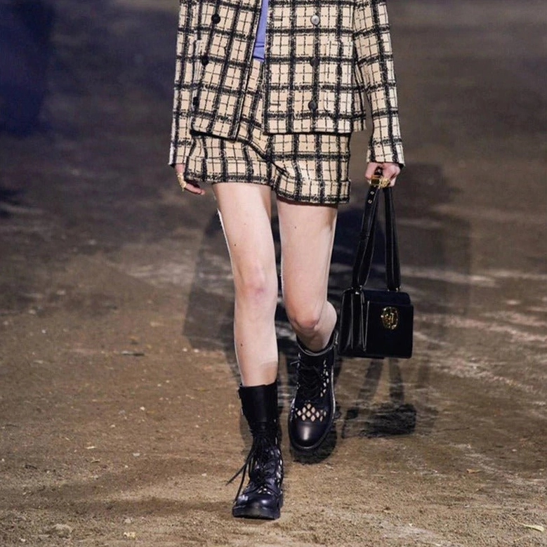 Black gothic lace-up combat pumps on runway model paired with checkered suit jacket alternative fashion show