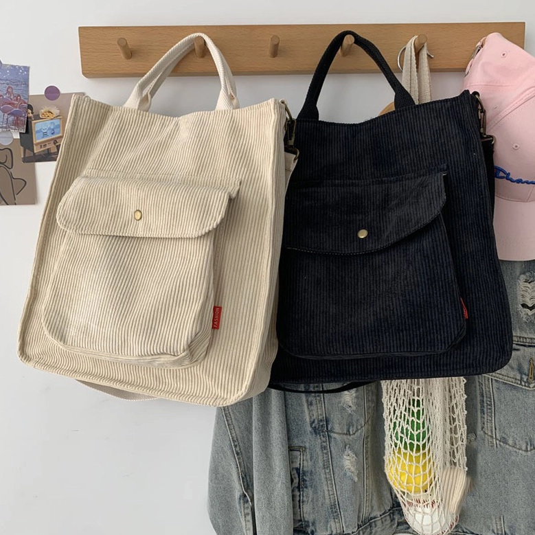 Beige and black corduroy gothic tote bags hanging on wall with vintage decor, showcasing alternative fashion styling options